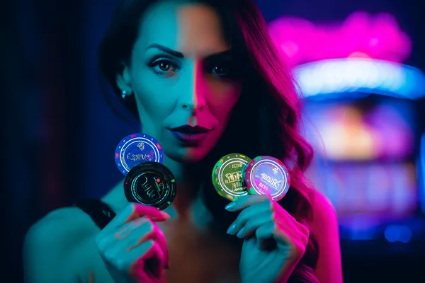 A woman smiling by bright slot machines showing lucky symbols, showcasing the exciting slot offerings at TKPK.